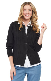 Woman wearing a black cardigan over a white shirt with a plain background